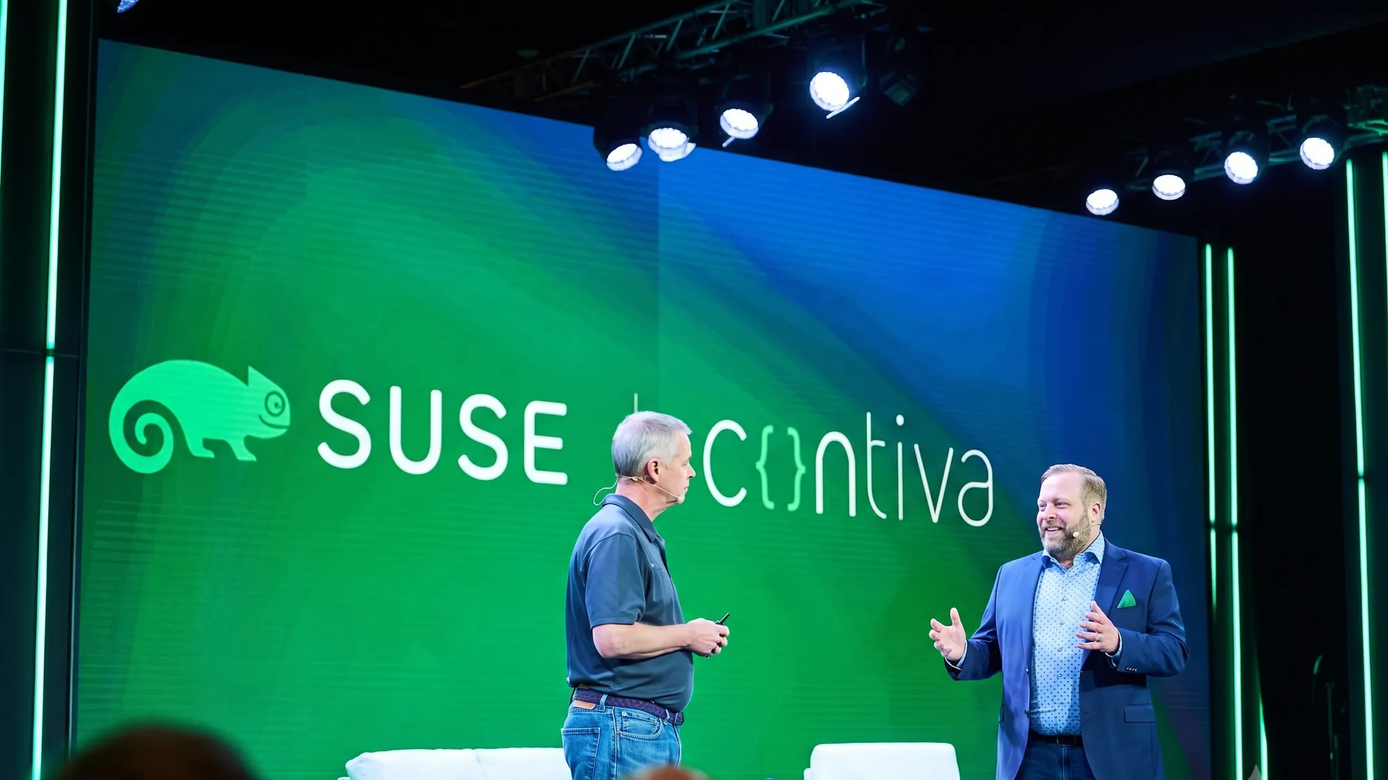 Robert Fels im Gespräch auf der SUSECON-Bühne, im Hintergrund die Logos von SUSE und Contiva